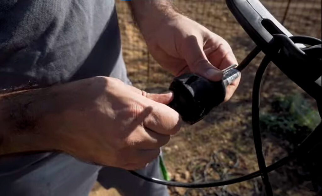 Representación de una electroazada o motoazada eléctrica conectándola a la corriente a través de una alargadera.