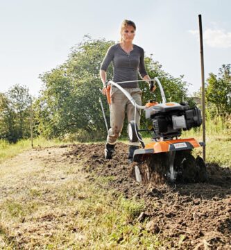 Mujer trabajando el suelo de su parcela con una motoazada
