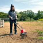 Mujer trabajando el suelo con una motoazada eléctrica o electroazada