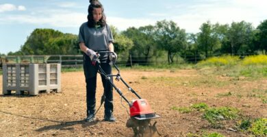 Mujer trabajando el suelo con una motoazada eléctrica o electroazada